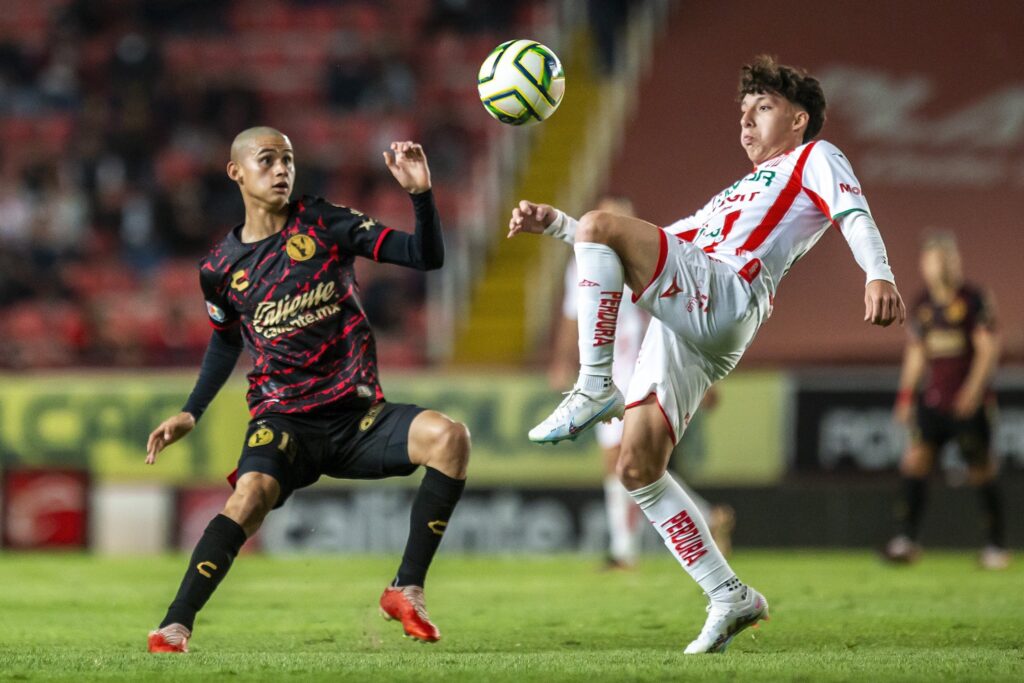 Cầu thủ Club Tijuana (áo đỏ đen) tranh bóng quyết liệt với đối thủ Club Necaxa (áo trắng xanh) trong trận đấu.